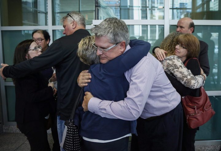 Gregg Perras, centre, spokesperson for the families of murder victims Jordan Segura, Zackariah Rathwell, Kaiti Perras, Joshua Hunter and Lawrence Hong is hugged after speaking with the media at the conclusion of the Alberta Review Board hearing in Calgary, Alta., Thursday, April 6, 2017.