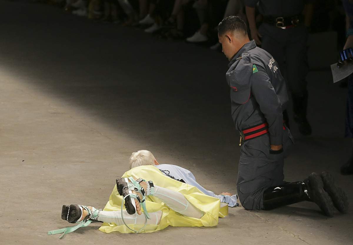 Model Tales Soares lies on the catwalk as a paramedic tends to him after he collapsed during Sao Paulo Fashion Week in Sao Paulo, Brazil, Saturday, April 27, 2019. A statement from organizers said that Soares died after taking ill while participating in Sao Paulo Fashion Week. (Leco Viana/Thenews2 via AP)