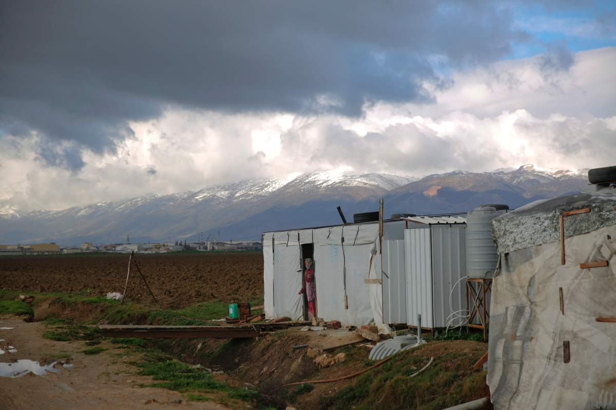 A woman stands at her tent door in an informal camp for Syrian refugees in the eastern Bekaa Valley town of Zahle, Lebanon, Monday, Dec. 31, 2018. (AP Photo/Hassan Ammar)