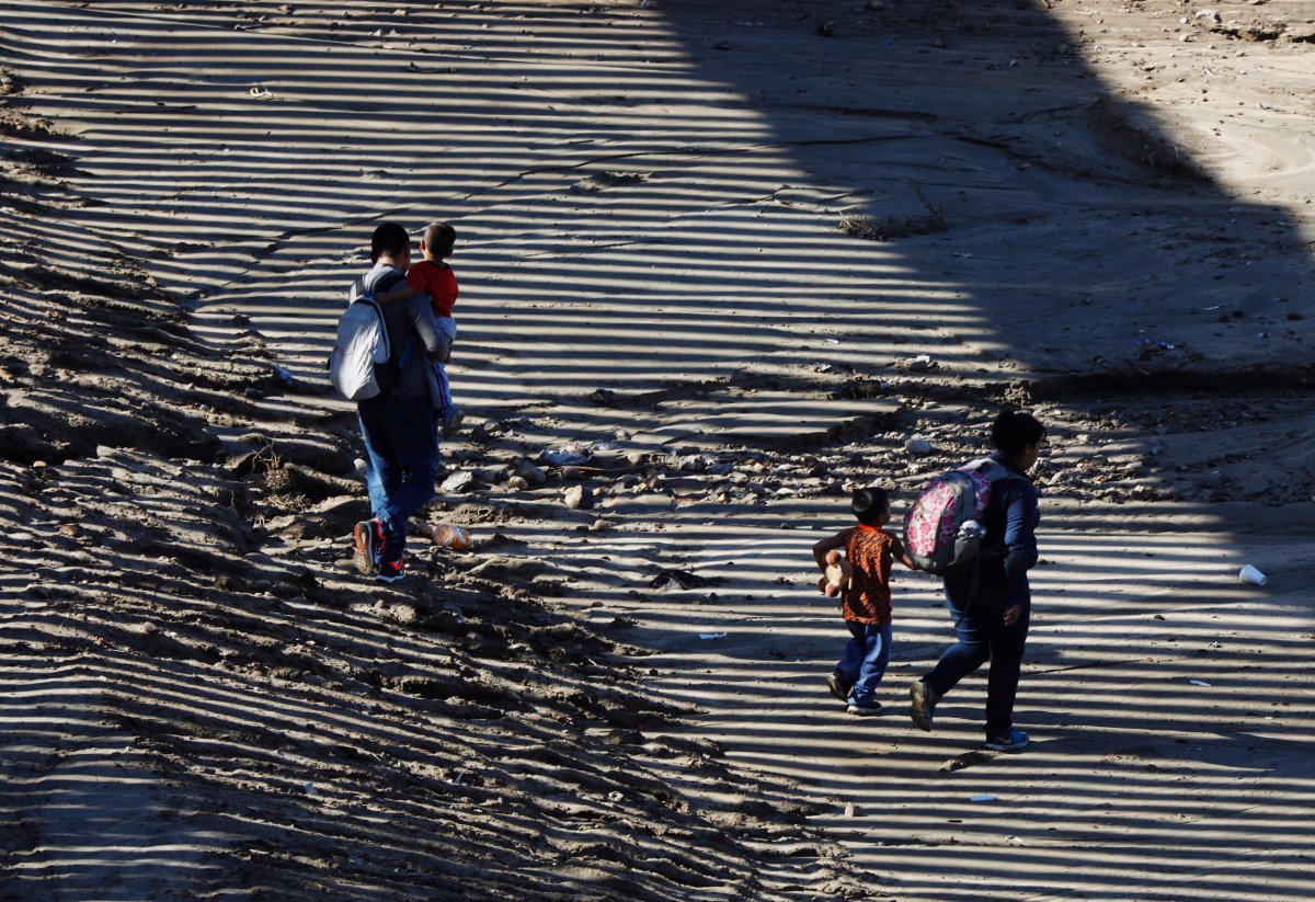 In this Dec. 9, 2018, file photo, the striped shadow of the U.S. border wall falls on a migrant family as they walk on U.S. soil near Imperial Beach, Calif., after squeezing through a small hole under the border wall aided by two local guides, seen from Tijuana, Mexico. 
