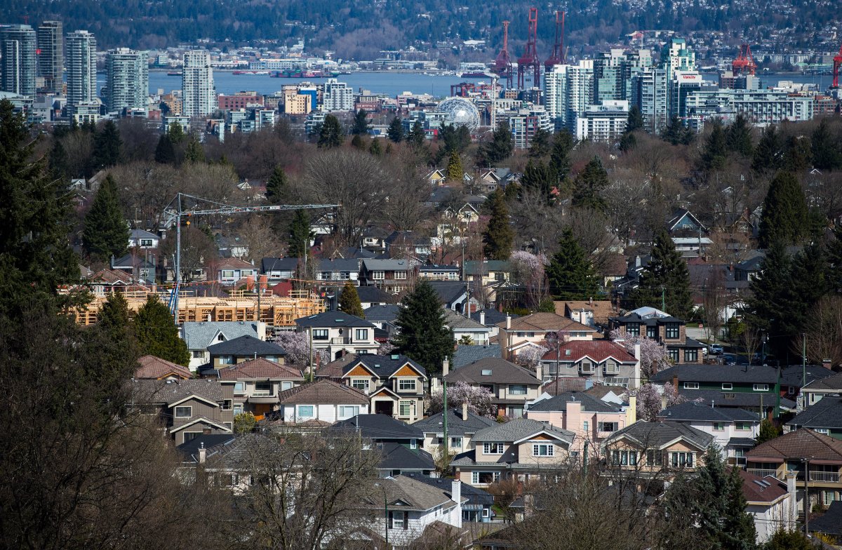 A condo building is seen under construction surrounded by houses as condo towers are seen in the distance in Vancouver, B.C., on Friday March 30, 2018. 