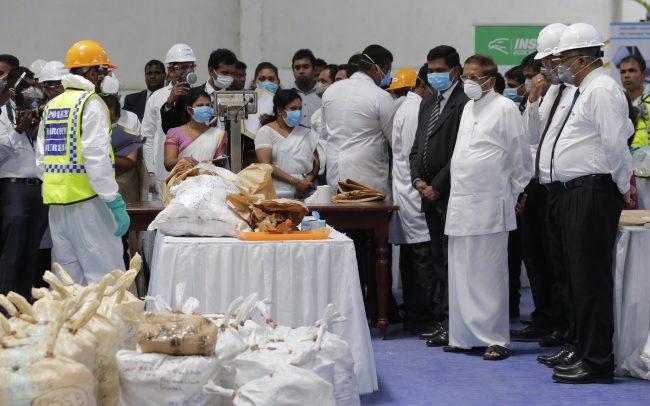 Sri Lankan president Maithripala Sirisena, third right, watches as officials in protective costumes prepare to destroy a haul of seized cocaine in Colombo, Sri Lanka, April 1, 2019.