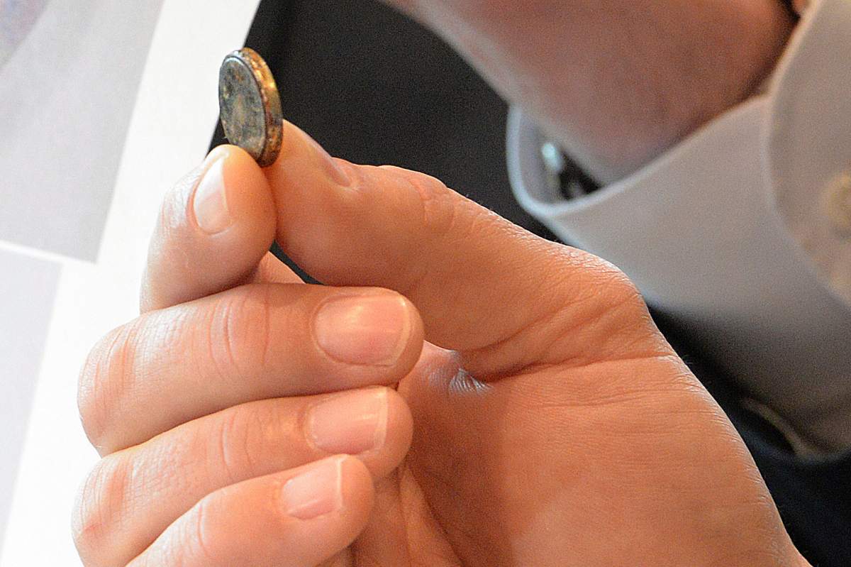 FILE PHOTO – A lawyer holds a battery that was removed from a toddler”s esophagus.