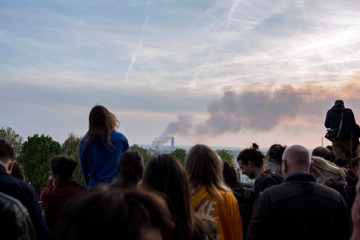 People watch Notre Dame Cathedral burning in Paris, Monday, April 15, 2019.