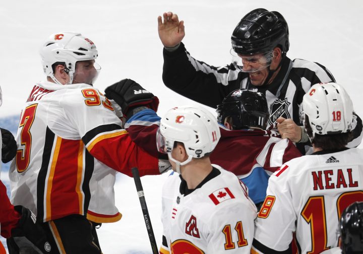Linesman Bryan Pancich, back, tries to separate Calgary Flames center Sam Bennett, front left, and Colorado Avalanche left wing Matt Calvert as they fight in the third period of Game 3 of a first-round NHL hockey playoff series, Monday, April 15, 2019, in Denver. The Avalanche won 6-2.
