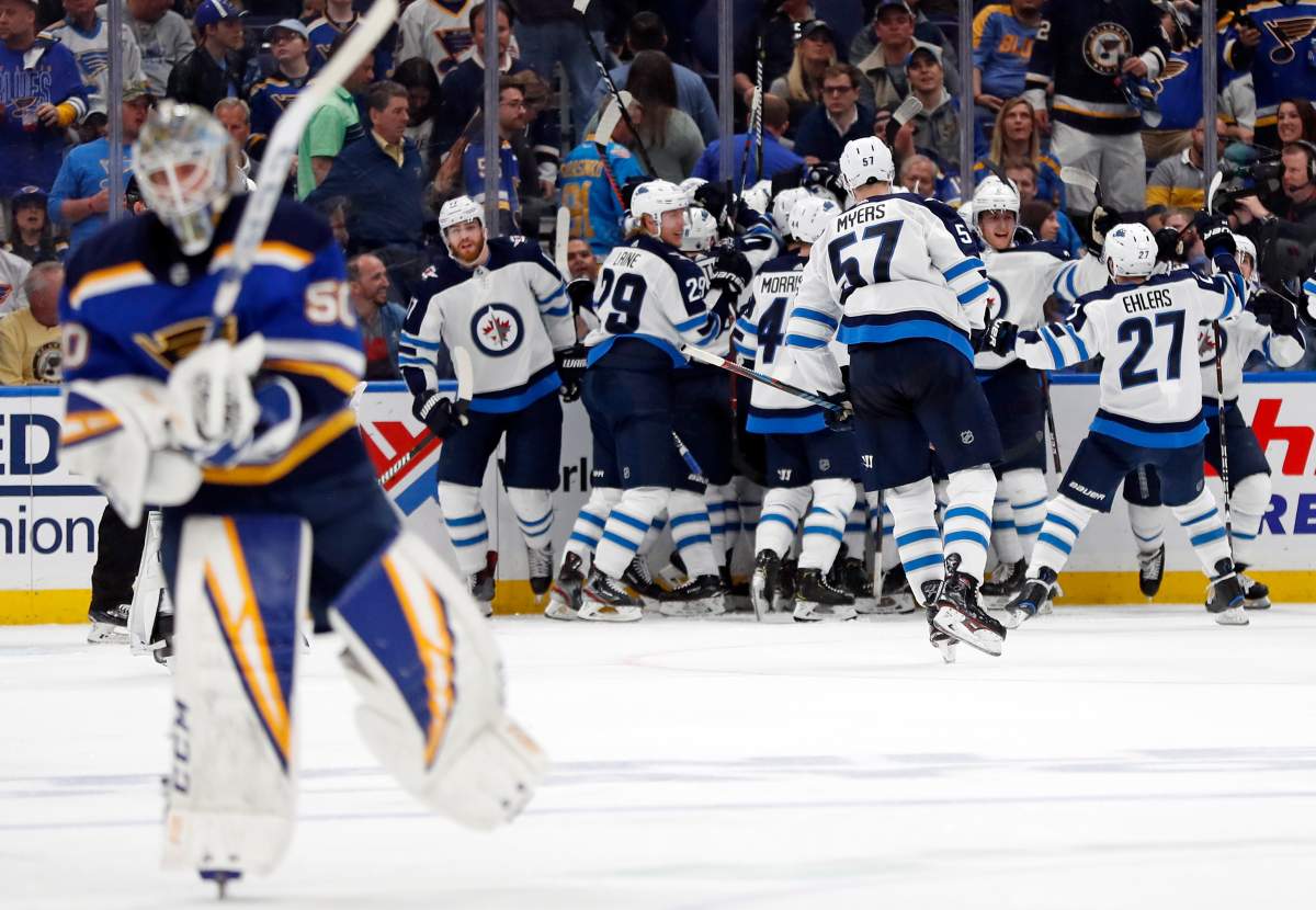 Winnipeg Jets celebrate as St. Louis Blues goaltender Jordan Binnington, left, skates to the bench after Jets left wing Kyle Connor scored during overtime in Game 4 of an NHL hockey first-round playoff series Tuesday, April 16, 2019, in St. Louis. The Jets won 2-1 to even the series 2-2. (AP Photo/Jeff Roberson).