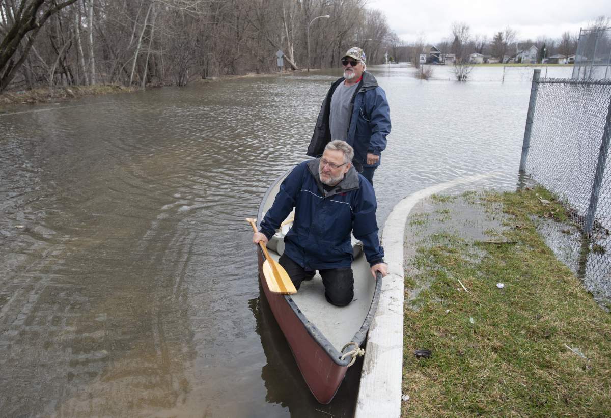 Mike Laurent (front) and Mario Vezina prepare to paddle a canoe through floodwaters, Wednesday, April 24, 2019, in Gatineau, Que.