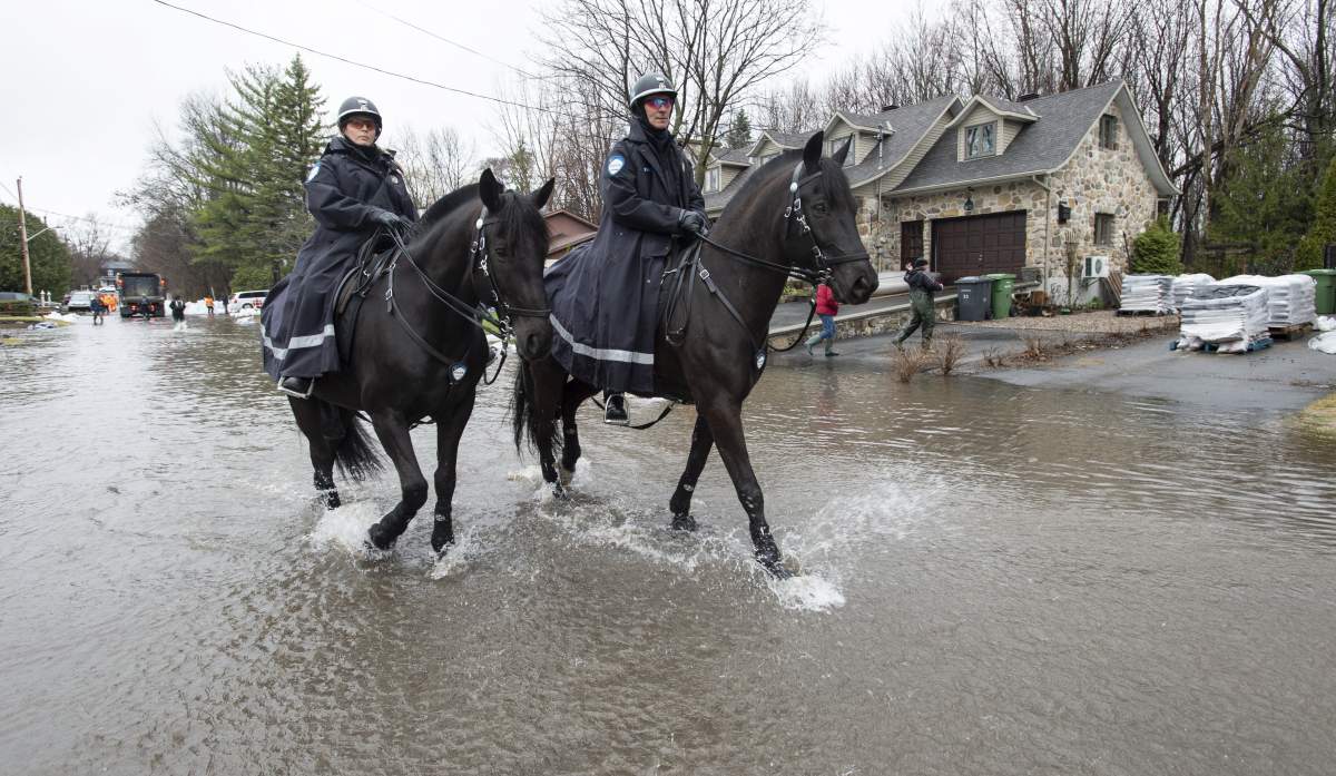 Members of the Montreal Police cavalry patrol a flooded neighbourhood on Ile Bizard, Que., on Wednesday, April 24, 2019.
