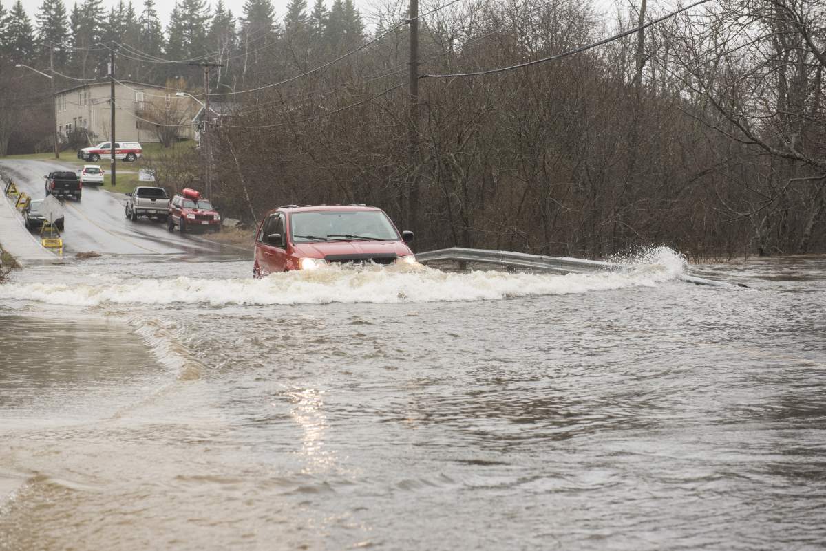 A vehicle drives through the flood waters of the St. John River on the only access road to the Dominion Park community in Saint John, N.B., on Wednesday, April 24, 2019.