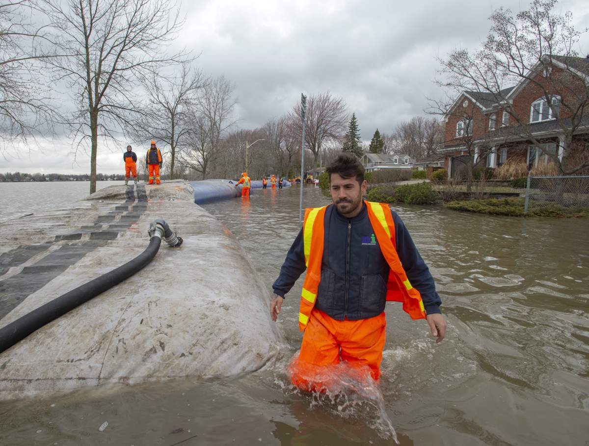 Workers install a temporary dam to hold back floodwaters Thursday, April 25, 2019, in Laval, Que.