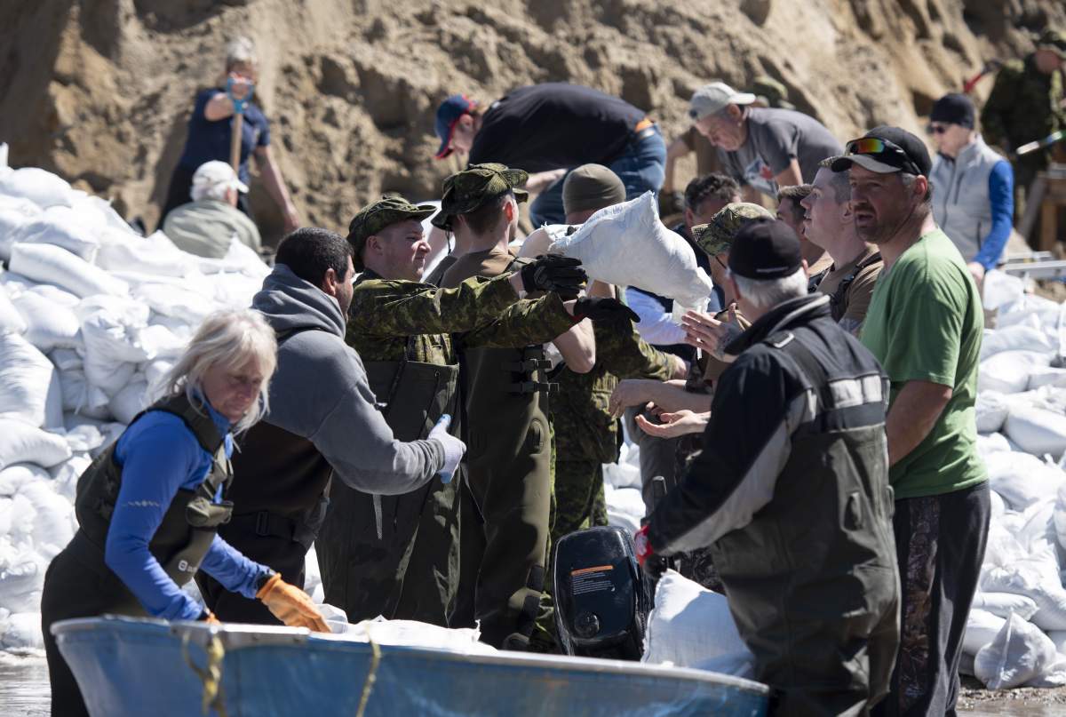 Volunteers, residents and Canadian Forces members form a human chain to load a boat with sandbags to protect houses on Voisine Road in Clarence-Rockland, east of Ottawa, on Sunday, April 28, 2019.
