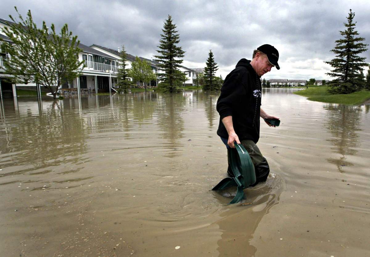 High River, Alta., resident Bill Rogers picks up some flood debris from the fifth fairway of the Highwood Golf Club which passes by his house, on Wednesday, June 8, 2005.
