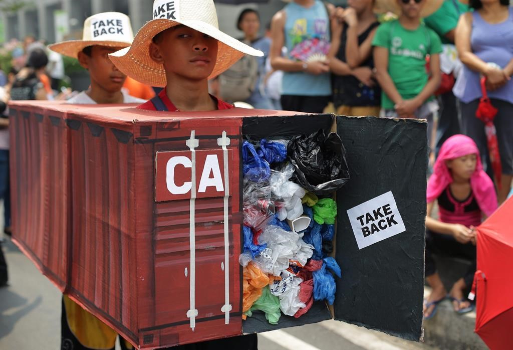 Filipino environmental activists wear a mock container vans filled with garbage to symbolize the 50 containers of waste that were shipped from Canada to the Philippines.