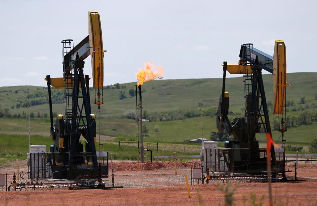 FILE -In this June 12, 2014 file photo, oil pumps and natural gas burn off in Watford City, N.D.
