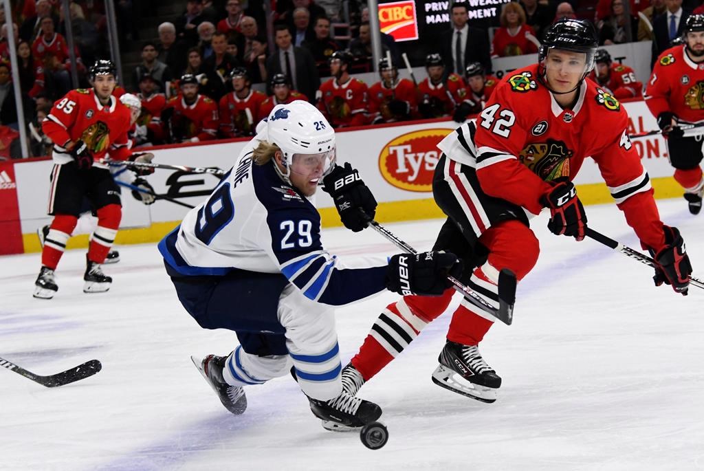 Winnipeg Jets right wing Patrik Laine (29) and Chicago Blackhawks defenseman Gustav Forsling (42) fight for the puck during the first period of an NHL hockey game on Monday, April 1, 2019, in Chicago. (AP Photo/Matt Marton).