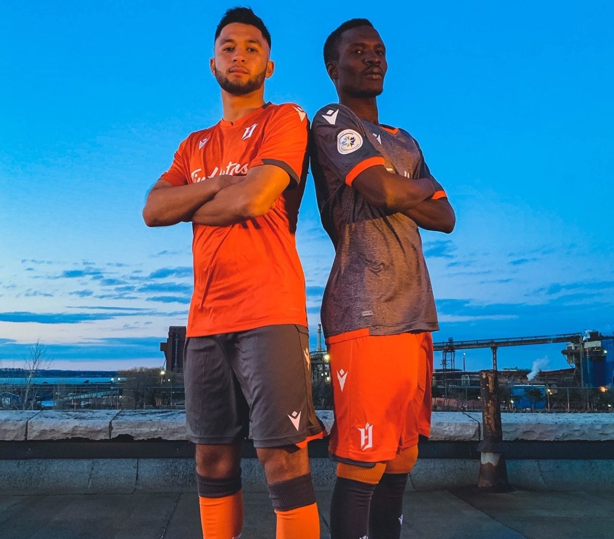 Forge FC players David Choiniere (left) and Elimane Cissé (right) show off the club's home (right) and away (left) kits ahead of the inaugural Canadian Premier League season.