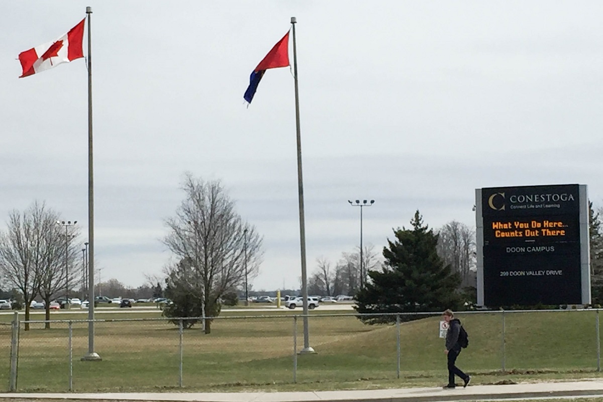 A student walks past the Conestoga College sign in Kitchener, Ont.