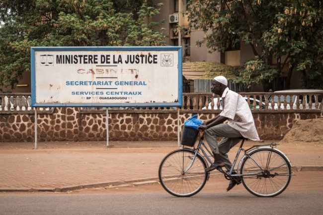 This picture taken on March 19, 2019 shows a man riding a bicycle in front of a sign of the ministry of justice in Ouagadougou. 


