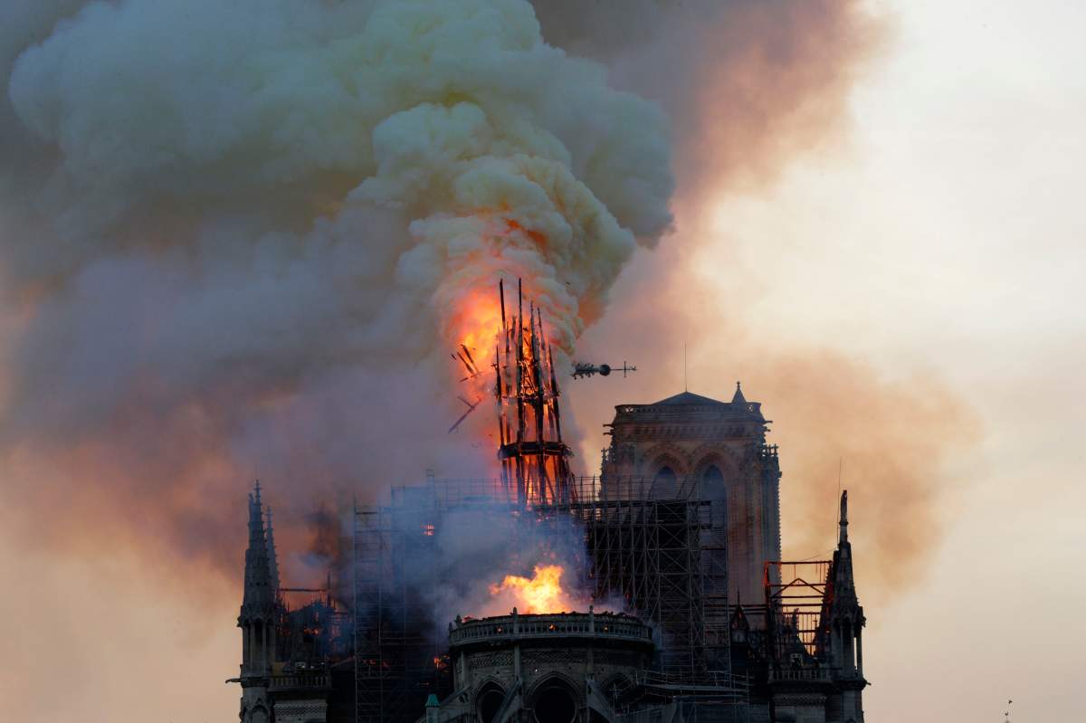 The steeple, engulfed in flames, collapses as the roof of the Notre Dame de Paris Cathedral burns on April 15, 2019, in Paris.