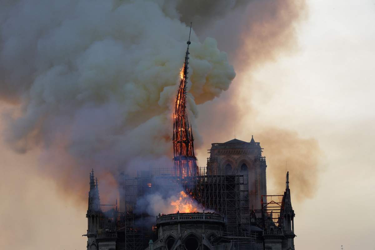 The steeple, engulfed in flames, collapses as the roof of the Notre Dame de Paris Cathedral burns on April 15, 2019, in Paris.