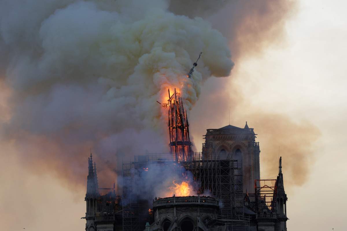The steeple, engulfed in flames, collapses as the roof of the Notre Dame de Paris Cathedral burns on April 15, 2019, in Paris.