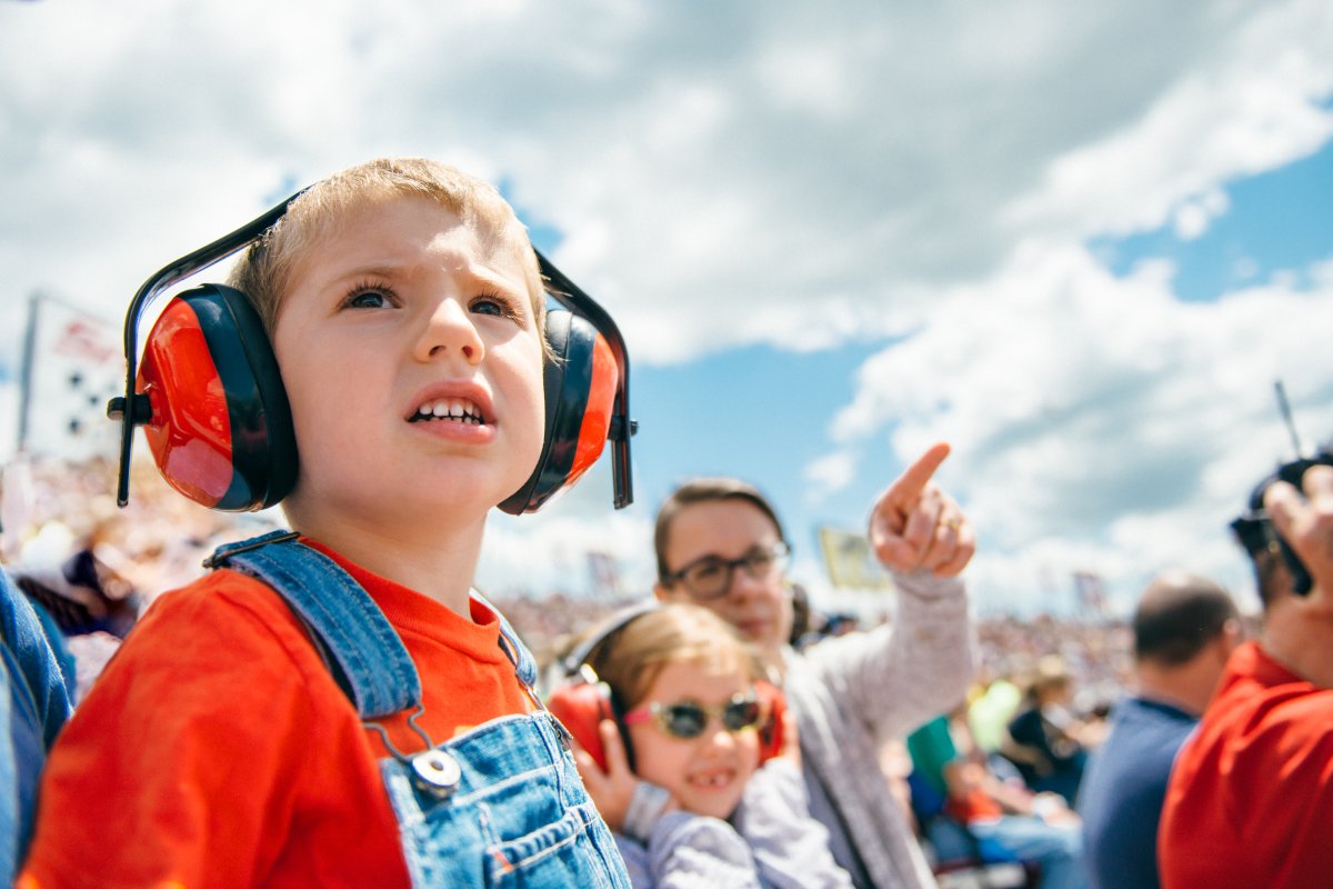 A child wears noise-cancelling headphones at a car race. 