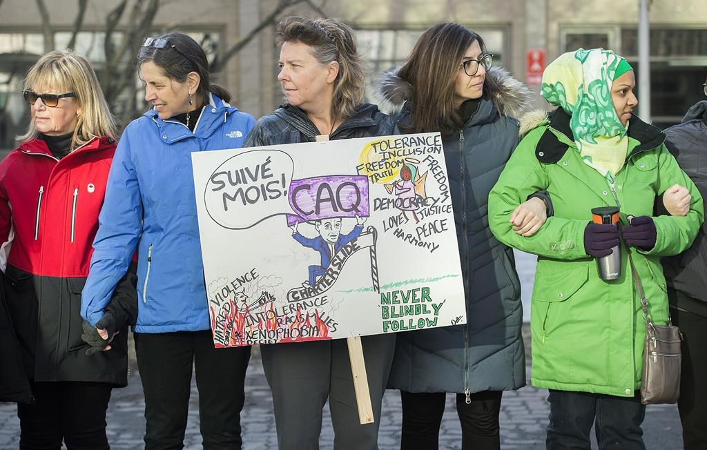 People hold up signs opposing the Quebec government's newly-tabled Bill 21 during a protest in Montreal, Wednesday, April 3, 2019.