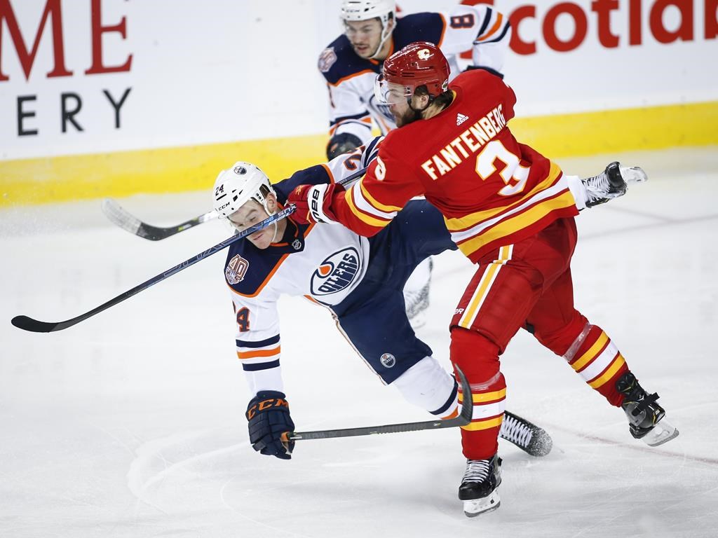 Edmonton Oilers' Brad Malone, left, is checked Calgary Flames' Oscar Fantenberg during third period NHL hockey action in Calgary, Saturday, April 6, 2019. Quebecor says it will follow through with its threat to scramble the signal of its TVA Sports channel for television subscribers of its competitor, Bell.