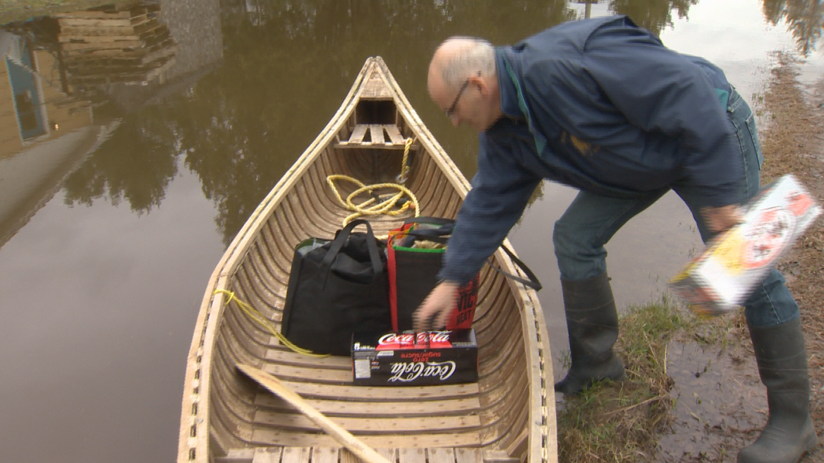 Maugerville resident Kent Shaw puts groceries in a canoe before paddling to his home.