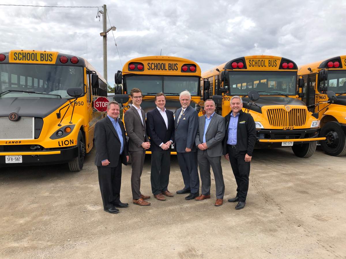 Transportation Minister Jeff Yurek (third from left) stands with fellow MPPs and a number of bus operators in the yard of Langs Bus Lines in south London, Ont.