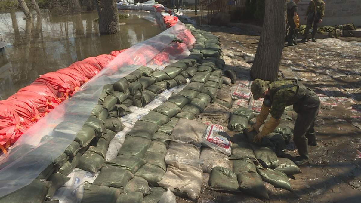 Canadian Army reservists work with municipal workers to plug a breach in a dike in Pierrefonds.
