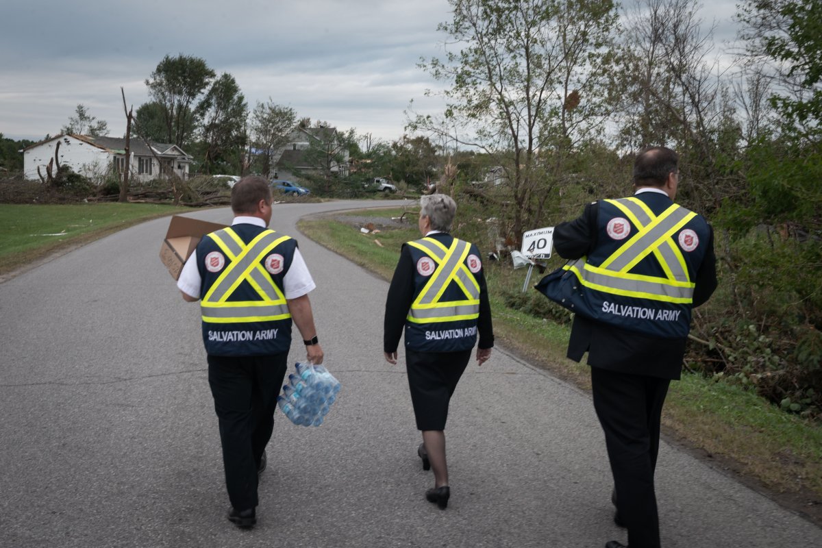 Three Salvation Army officials walk down a road in Dunrobin in shortly after a tornado ripped through the west Ottawa community on Sept. 21, 2018. They went door-to-door, handing out water bottles and checking on affected residents.