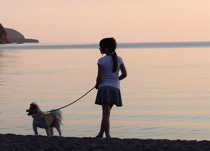 A girl and her dog are seen by the water in a park. Tuesday, May 21, 2019.