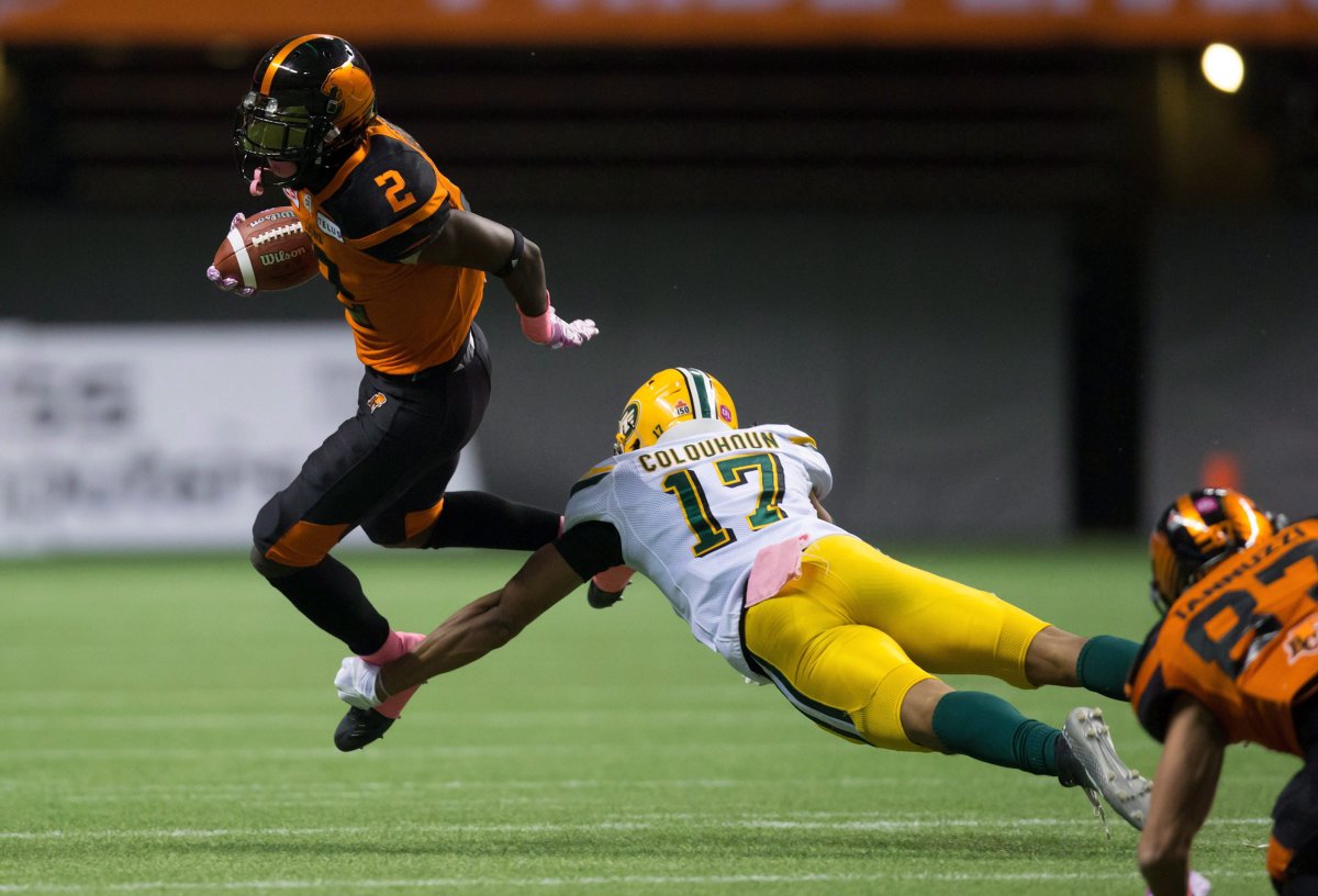 B.C. Lions' Chris Rainey, left, is stopped by Edmonton Eskimos' Arjen Colquhoun during the first half of a CFL football game in Vancouver, B.C., on Saturday October 21, 2017. 