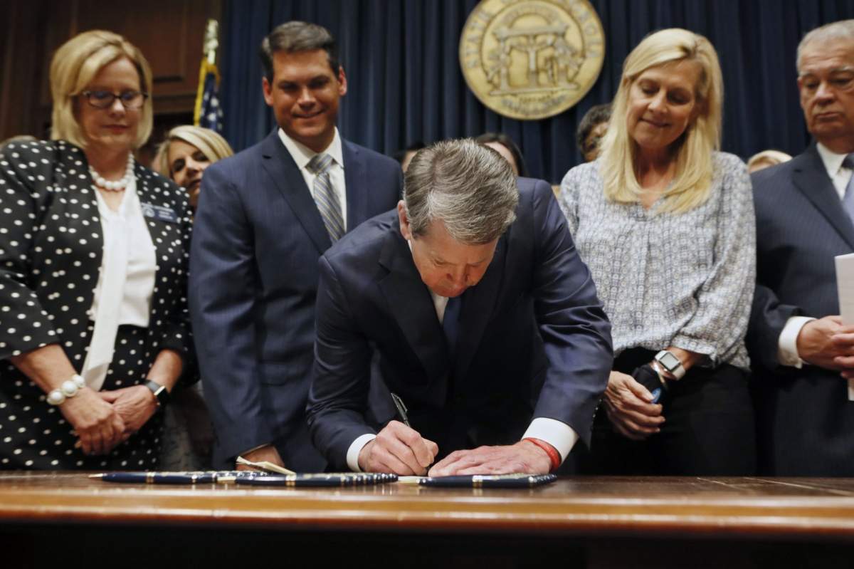 Georgia’s Republican Gov. Brian Kemp, center, signs legislation in Atlanta, banning abortions once a fetal heartbeat can be detected, which can be as early as six weeks before many women know they’re pregnant.