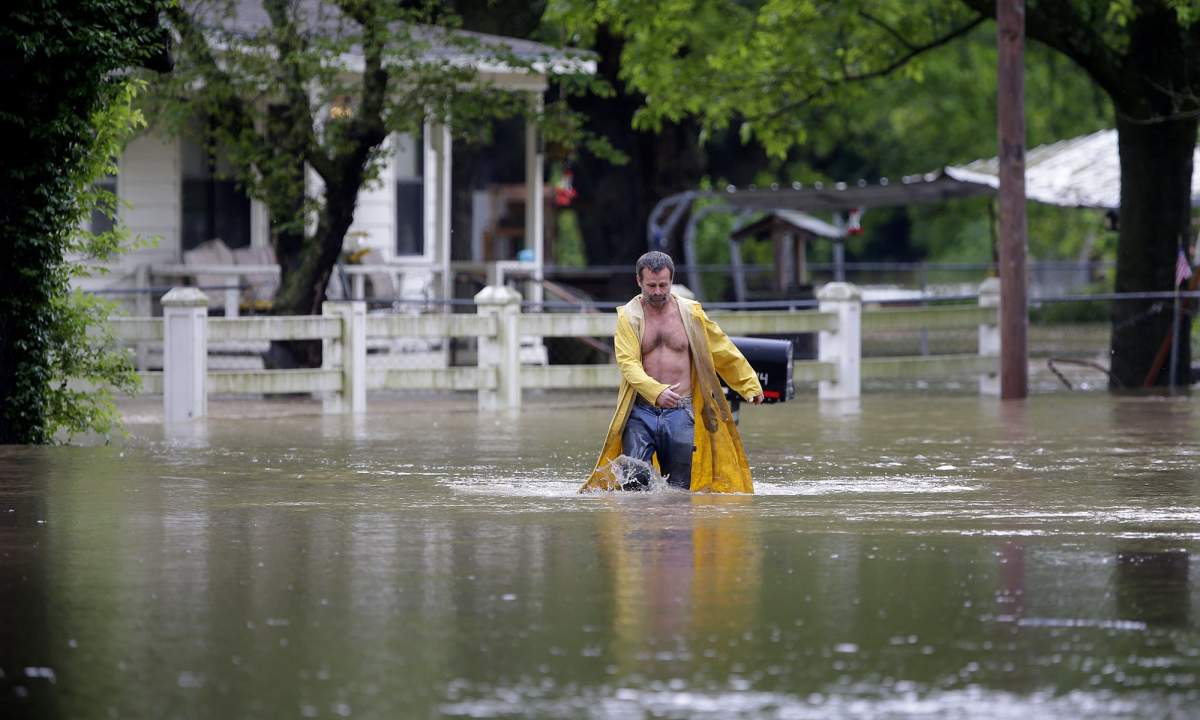 David Dick wades out of the water after checking on his flooded home in Sperry, Okla., Tuesday, May 21, 2019. A tornado touched down near Tulsa International Airport amid storms in the Southern Plains that brought a deluge of rain and powerful winds, closing an interstate and flipping campers at a raceway.
