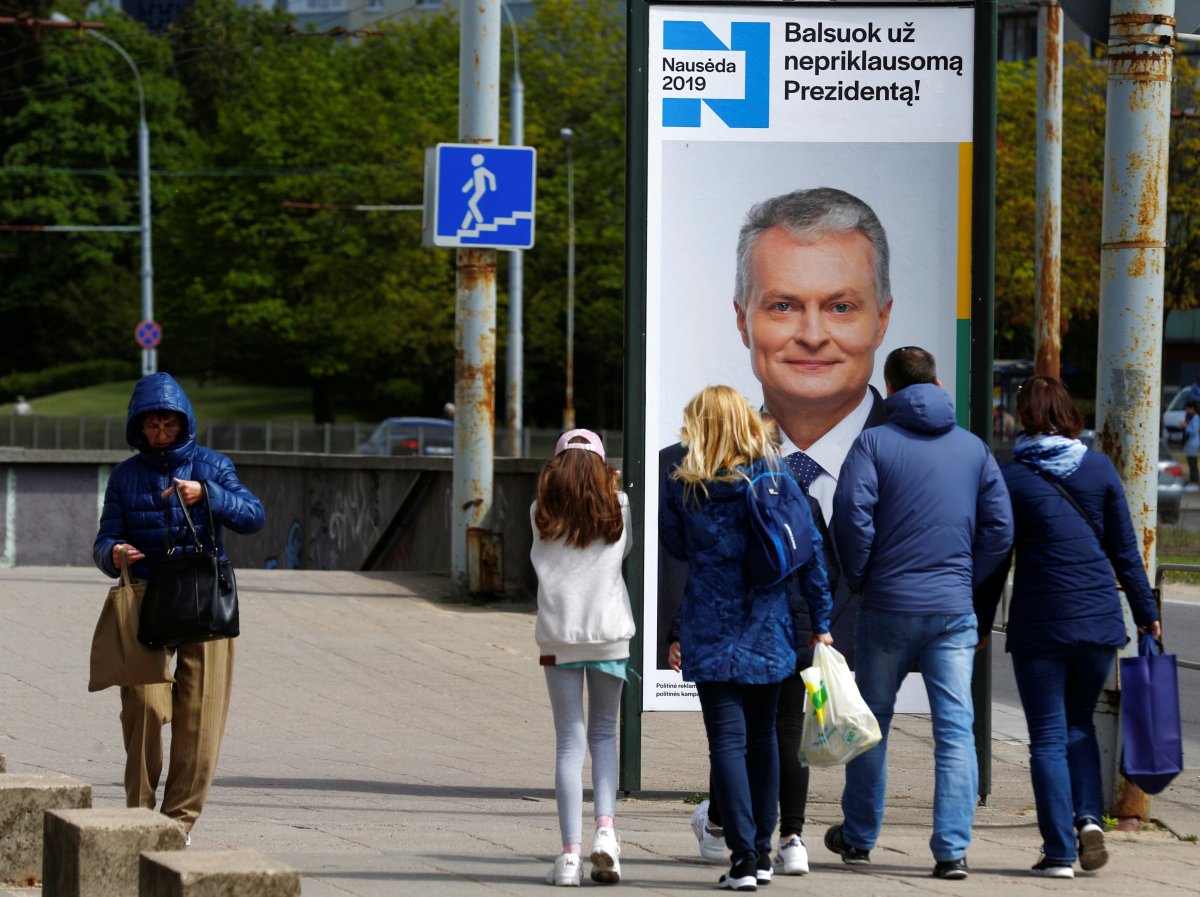 People walk past an election campaign placard of a Lithuanian presidential candidate Gitanas Nauseda in Vilnius, Lithuania May 9, 2019. 