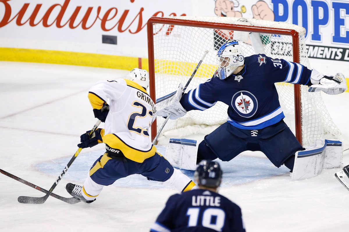 Winnipeg Jets goaltender Laurent Brossoit (30) saves the shot from Nashville Predators' Rocco Grimaldi (23) as Jets' Tyler Myers (57) defends during third period NHL action in Winnipeg on Friday, March 1, 2019. THE CANADIAN PRESS/John Woods.