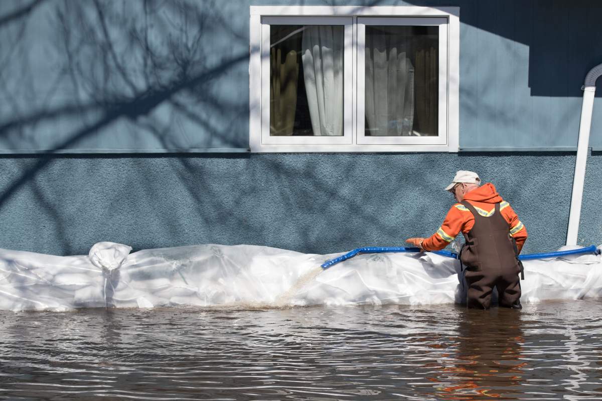 A man inspects a hose near a home in the west Ottawa community of Constance Bay on Sunday, April 28, 2019.