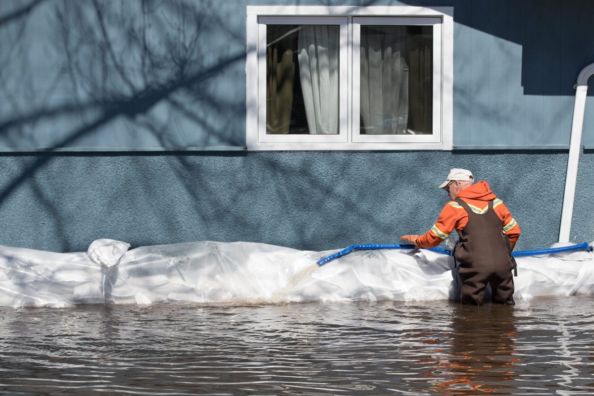 A man inspects a hose near a home in the west Ottawa community of Constance Bay on Sunday, April 28, 2019.