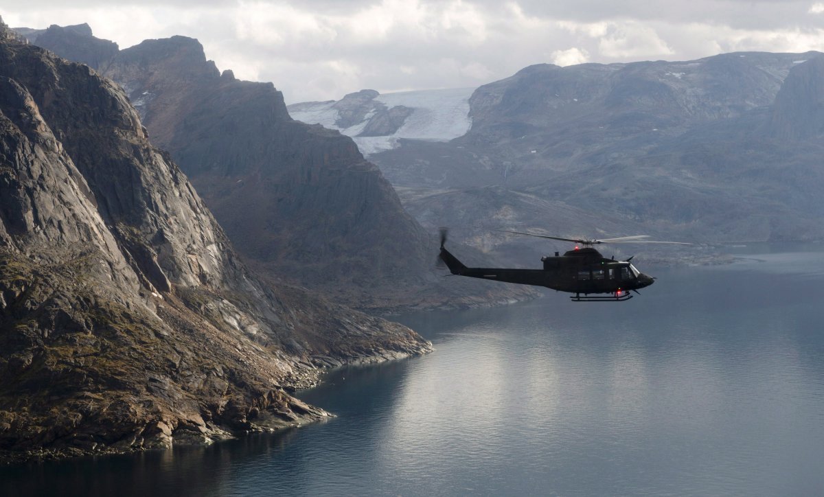 A Canadian military Griffon helicopter flies along the shoreline of Baffin Island on Tuesday August 26, 2014.