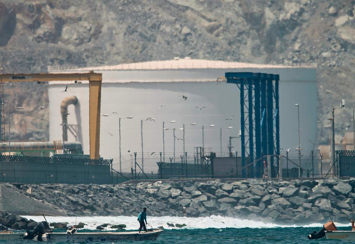 A fisherman prepares his boat near an oil storage tank in Fujairah, United Arab Emirates, Monday, May 13, 2019.