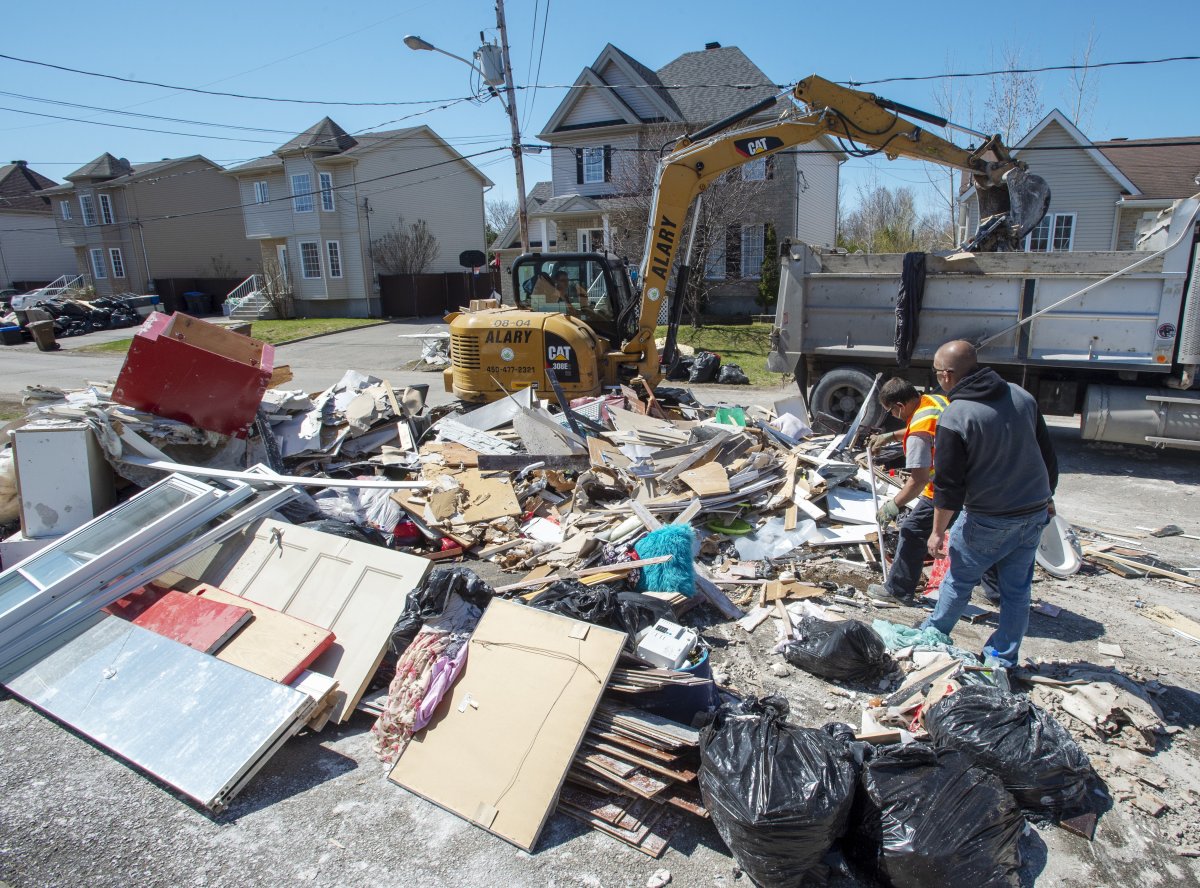 Workers clean up debris as clean up continues in certain sectors of in Sainte-Marthe-sur-la-Lac, Que., Monday, May 6, 2019. A dike broke last week causing widespread flooding and forcing thousands of people to evacuate.