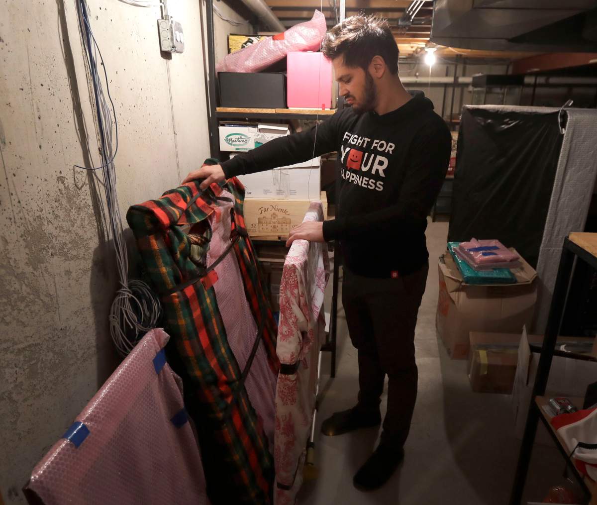 In this Tuesday, April 2, 2019, photo, former NHL player Dan Carcillo looks through some of his memorabilia that is still wrapped that his grandfather collected in the basement of Carcillo’s rural home in Homer Glen, Ill.