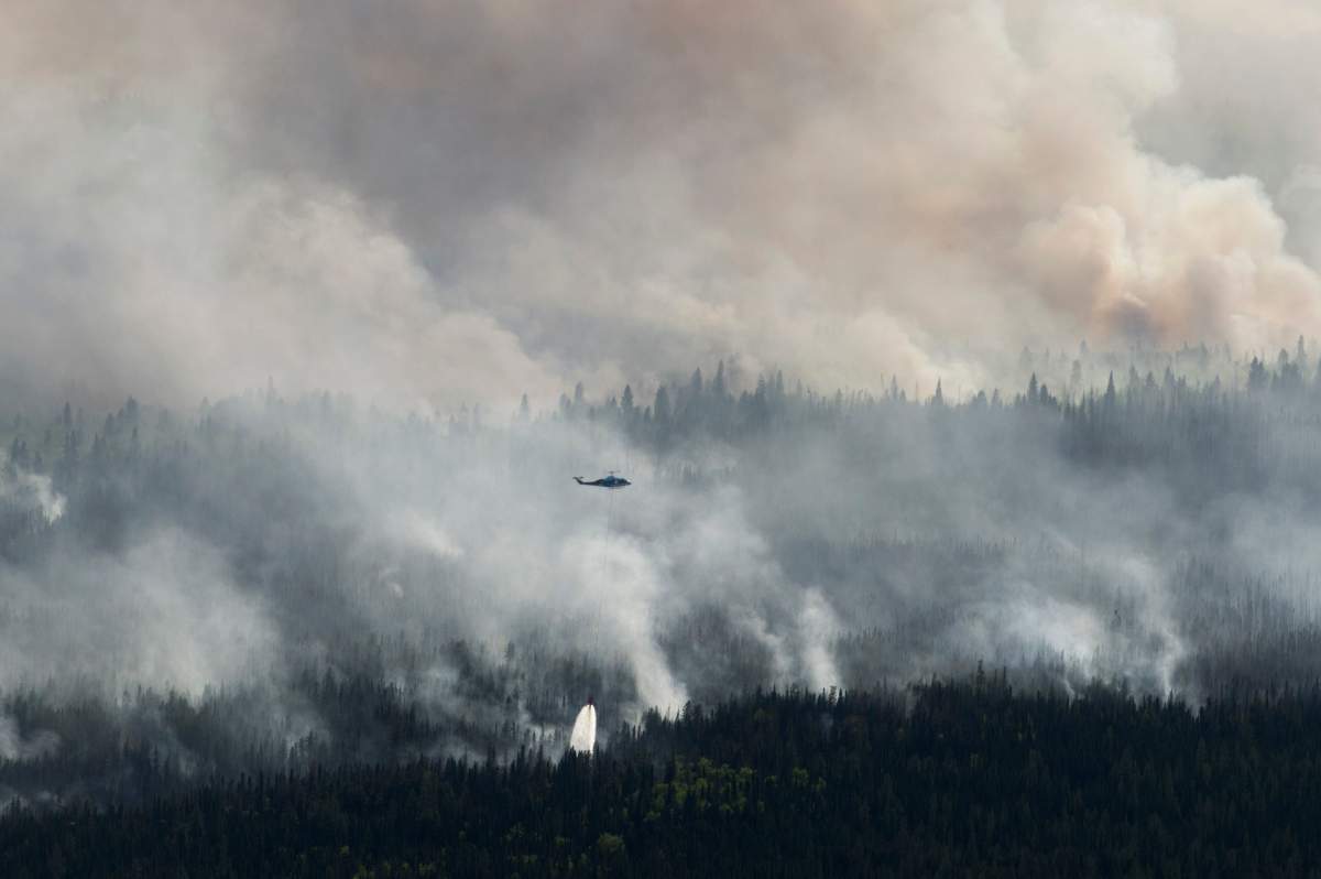 A helicopter drops a bucket of water on the Chuckegg Creek wildfire west of High Level, Alta., in a Saturday, May 25, 2019, handout photo.