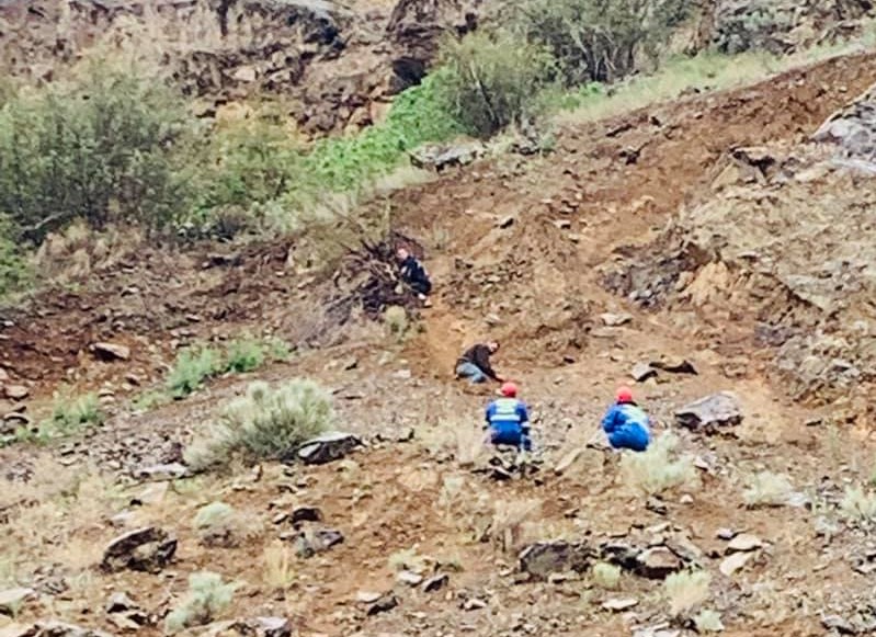 Two members with the Osoyoos fire department, pictured in blue, coax two stranded hikers off of a steep mountain west of Osoyoos on Saturday afternoon. 