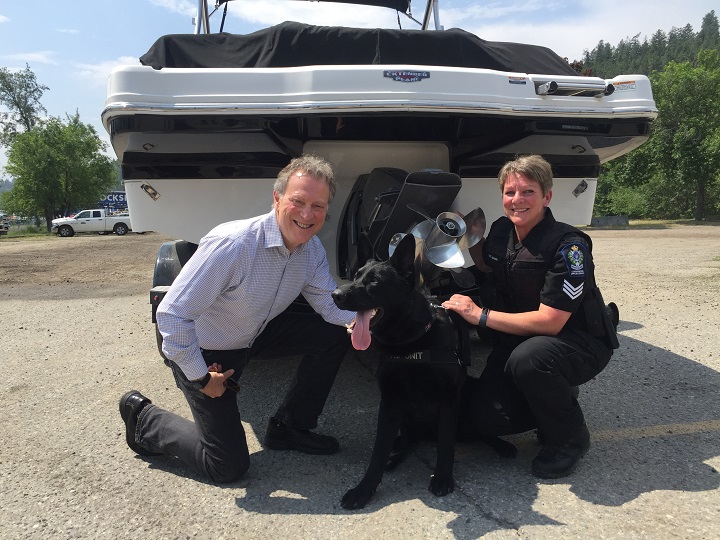B.C. Minister of Environment George Heyman, Major the dog and Sgt. Cynthia Mann pose for a photo in front of a boat.