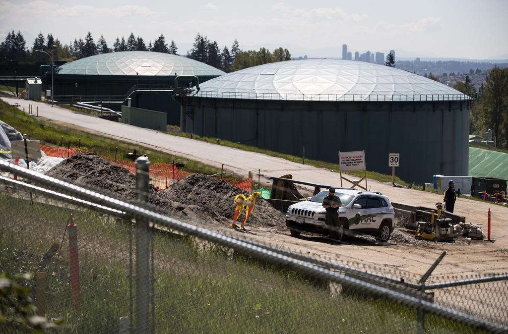 A security guard stands nearby construction workers at the Kinder Morgan Burnaby Terminal tank farm, the terminus point of the Trans Mountain pipeline, in Burnaby, B.C., on Tuesday, April 30, 2019.