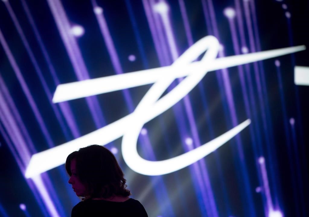 A woman is silhouetted as the Telus Corp. logo is displayed on a screen during a company event in Vancouver, B.C., on Friday October 2, 2015. Telus Corp. raised its dividend as it reported a first-quarter profit of $437 million, up from $412 million a year ago. THE CANADIAN PRESS/Darryl Dyck.