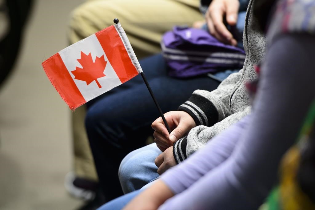 A young new Canadian holds a flag as she takes part in a citizenship ceremony on Parliament Hill in Ottawa on Wednesday, April 17, 2019, to mark the 37th anniversary of the Canadian Charter of Rights and Freedoms.